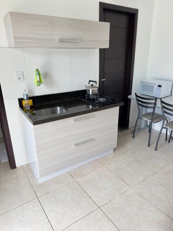Cozinha compacta com pia, micro-ondas, mesa e cadeiras