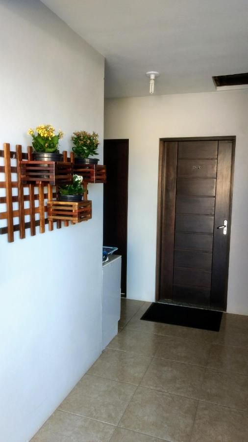 Entrada do térreo com jardineira de madeira, flores e porta escura