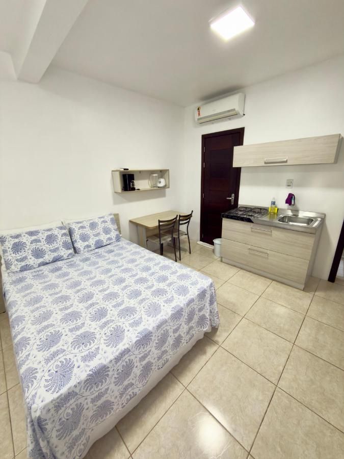 Quarto de casal com ar-condicionado e cozinha compacta ao fundo