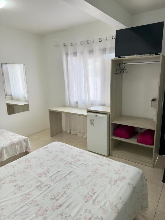 Quarto com TV, armário, frigobar e cama de roupa floral
