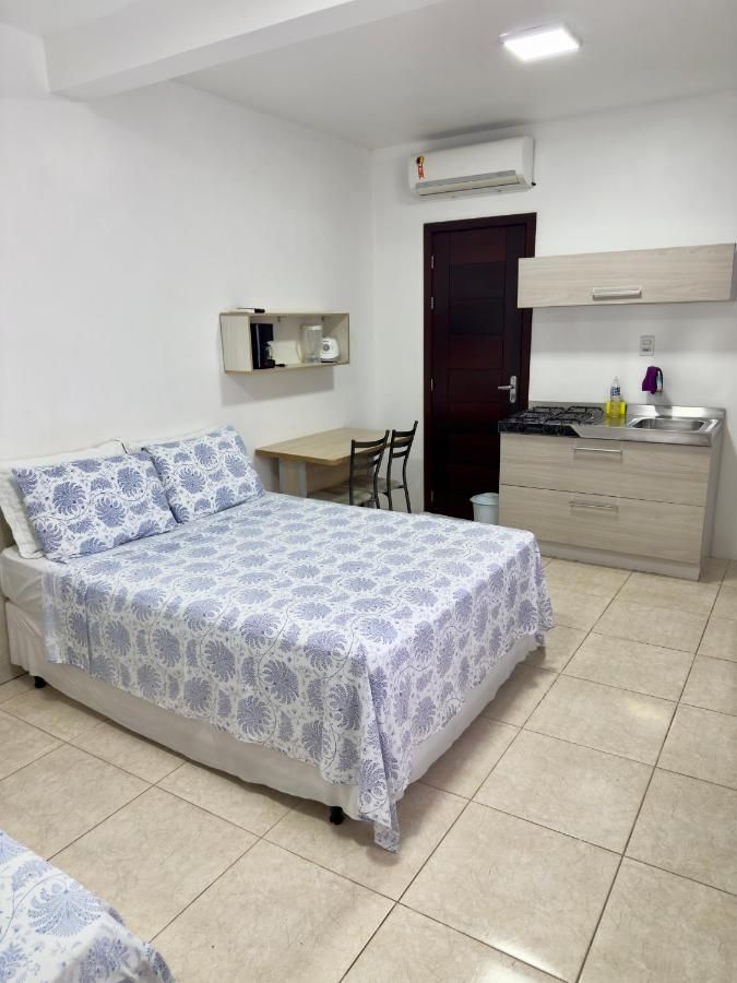 Quarto de casal com ar-condicionado, mesa pequena e cozinha compacta
